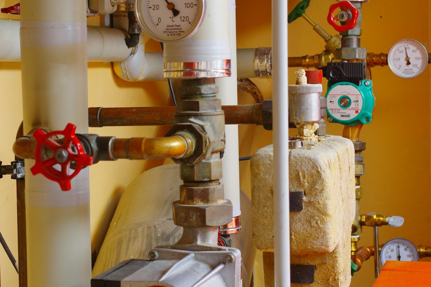 Heating pipework with red valves and pressure gauges