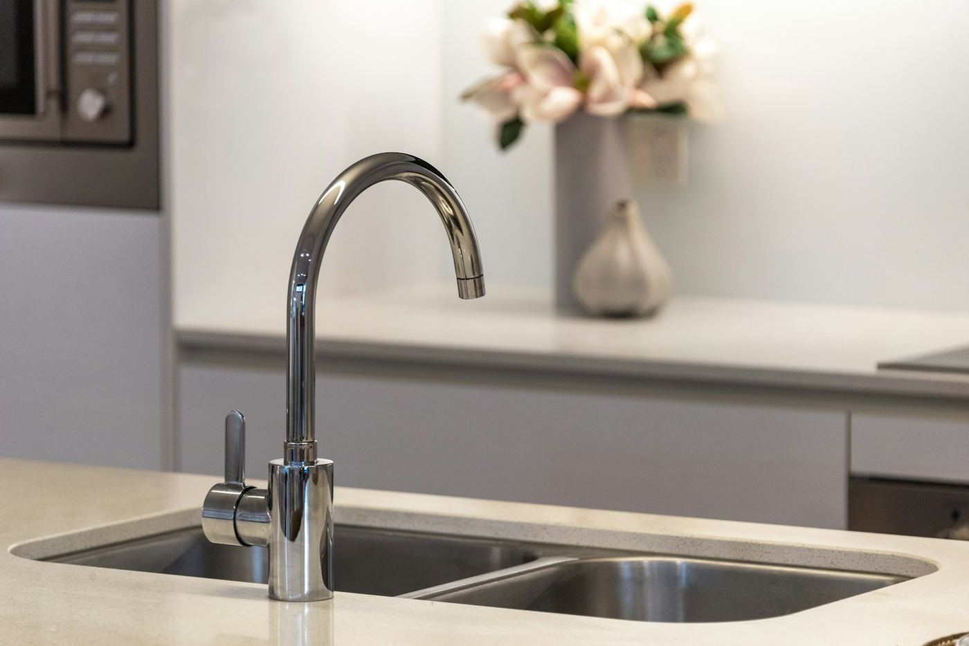 A chrome kitchen tap over a stainless steel sink
