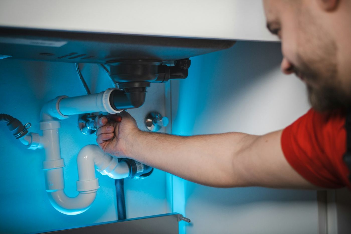 A plumber working on the pipes under a kitchen sink