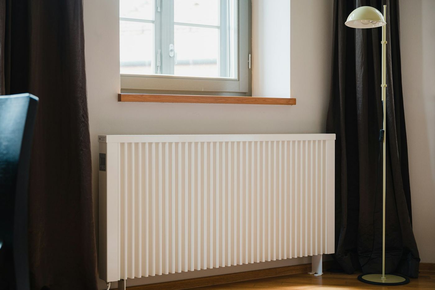A white radiator under a window in a bright room